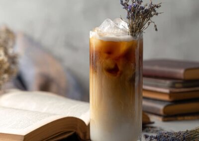 Iced lavender London Fog tea latte with distinct milk and tea layers, garnished with lavender next to an open book.
